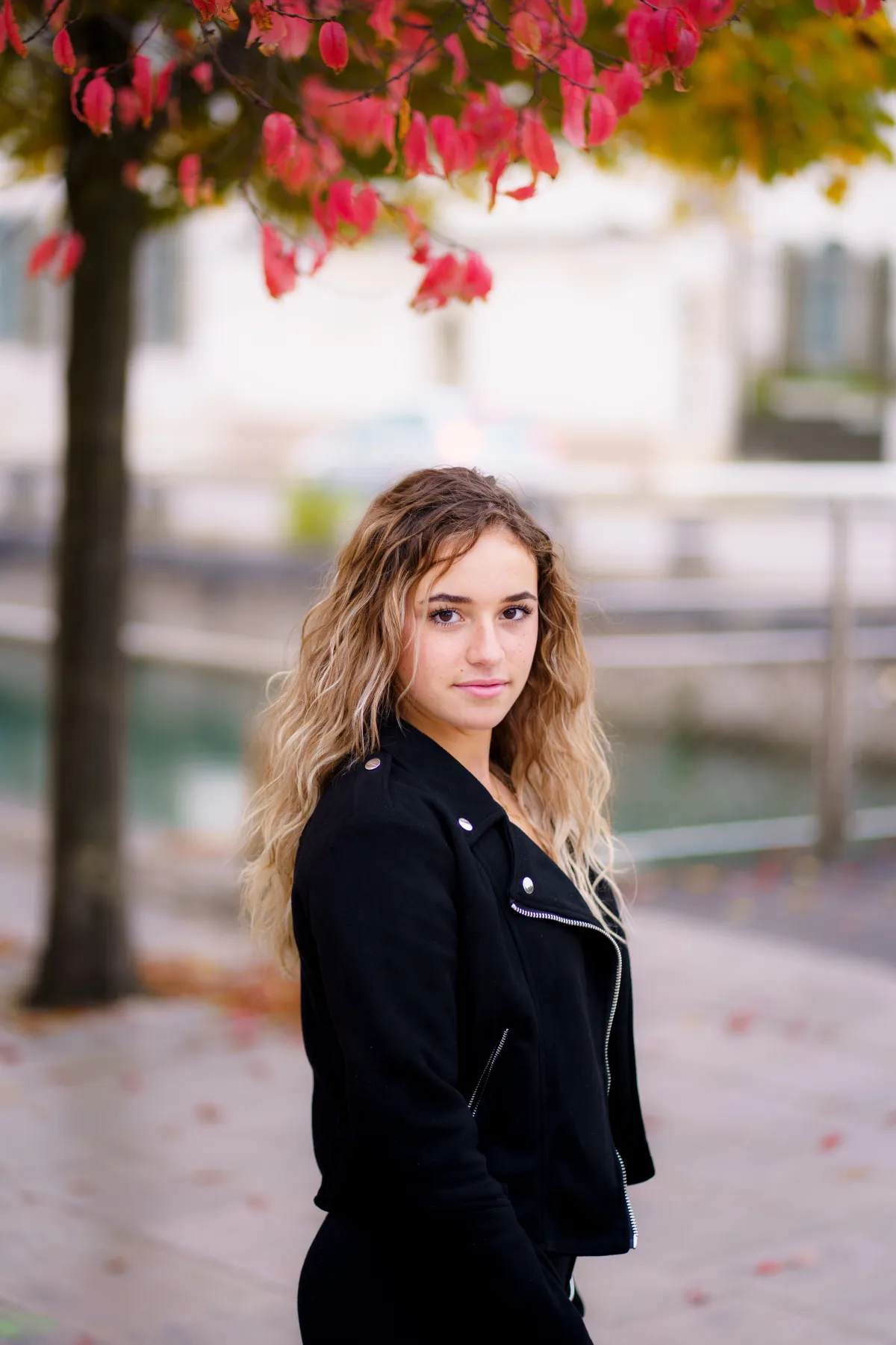 Femme en perfecto noir au bord d'un canal avec feuillages d'automne